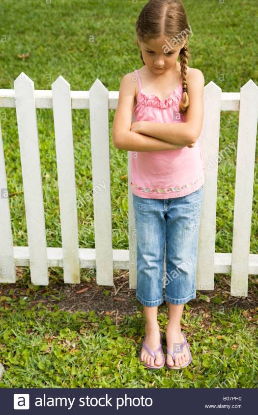 little-girl-standing-against-fence-with-arms-folded-B07PH0.jpg